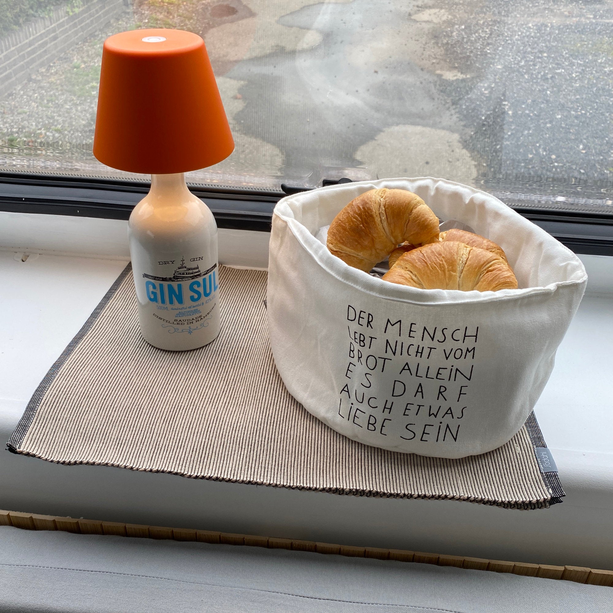 Frühstückskörbchen mit frischen Croissants steht neben einem praktischem Lampenaufsatz für leere Flaschen.